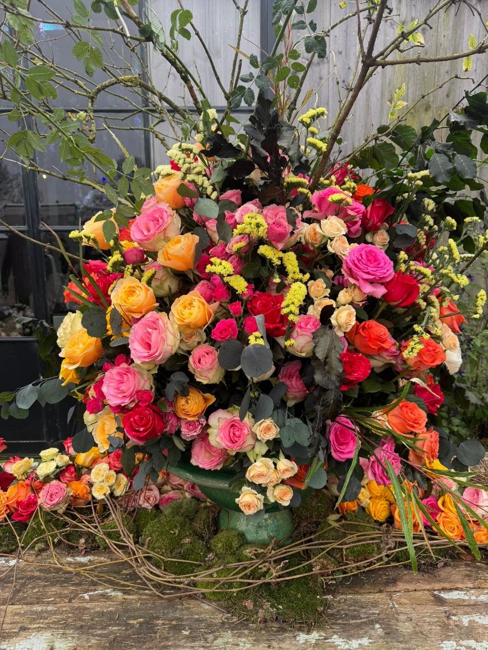 Vibrant outdoor floral arrangement featuring multicolored roses and branches at Aalsmeer flower trade show